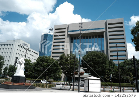 A city square with modern buildings and sculptures, under a clear daytime sky. A city square with modern buildings and sculptures, under a clear daytime sky. 142252579