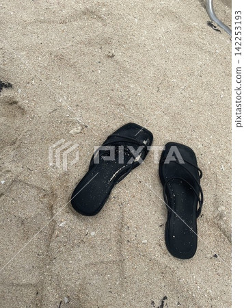 A black flip-flop placed on the sand on a beach in Ishigaki Island. (Tropical beaches, swimming, travel, summer vacation, silly) A black flip-flop placed on the sand on a beach in Ishigaki Island. (Tropical beaches, swimming, travel, summer vacation, silly) 142253193