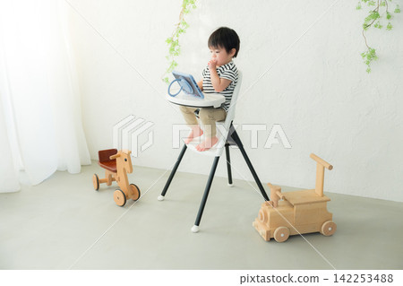 一個孩子坐在兒童椅上看影片。 一個孩子坐在兒童椅上看影片。 142253488