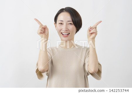 一位微笑的女子在白色背景前雙手指向前方。 142253744