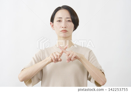 Woman making an "X" with her fingers; middle-aged; white background Woman making an "X" with her fingers; middle-aged; white background 142253755