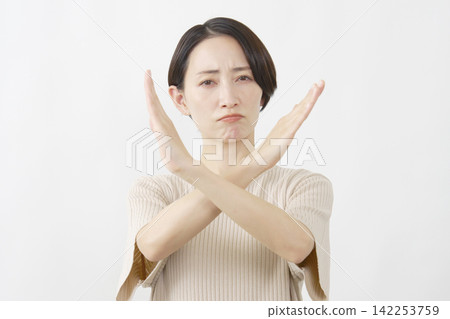 一名女子在白色背景前用雙臂擺出一個大大的「X」形。 142253759