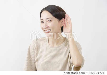 A middle-aged woman listening intently to a white background. A middle-aged woman listening intently to a white background. 142253771