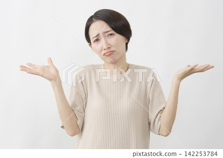 一名女子在白色背景前舉起雙臂，做出無助的姿勢。 142253784