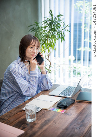 A woman working indoors using a laptop. A woman working indoors using a laptop. 142254361