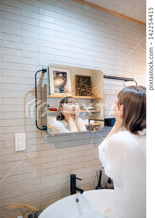 A woman spending time in a bathroom with a sink. A woman spending time in a bathroom with a sink. 142254415
