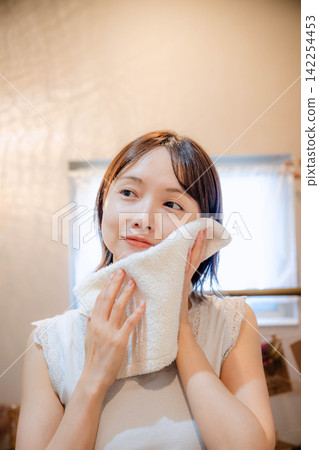 A young lady wiping his face with a towel A young lady wiping his face with a towel 142254453