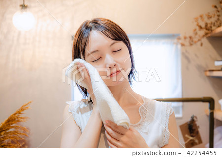 A young woman holding a towel indoors A young woman holding a towel indoors 142254455