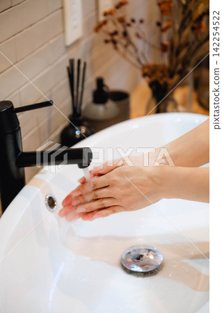 A woman's hands washing with running water A woman's hands washing with running water 142254522