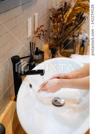 A woman washes her hands with water and cleans. A woman washes her hands with water and cleans. 142254526