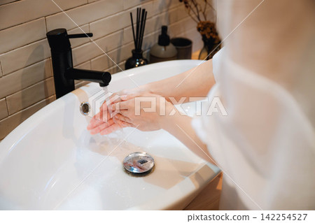 一位女性習慣在水龍頭處洗手 一位女性習慣在水龍頭處洗手 142254527