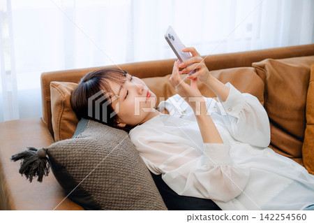 A young woman looking at her smartphone indoors A young woman looking at her smartphone indoors 142254560