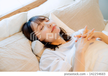 一位年輕女子在臥室的床上休息 一位年輕女子在臥室的床上休息 142254683