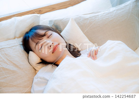 A young woman sleeping in a bedroom bed A young woman sleeping in a bedroom bed 142254687