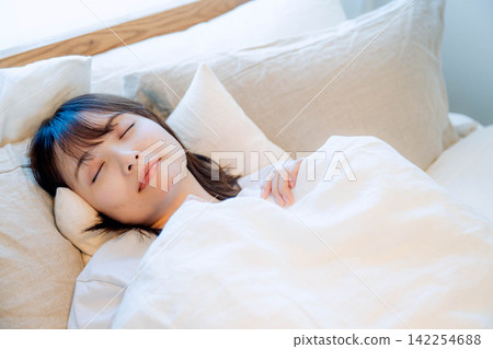 A young woman sleeping in a bed A young woman sleeping in a bed 142254688