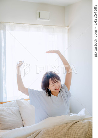Young woman waking up in bed in the morning Young woman waking up in bed in the morning 142254695