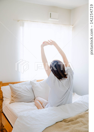 一天早晨,一位女士在臥室的床上醒來。 一天早晨,一位女士在臥室的床上醒來。 142254719