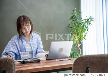 一位女士正在用筆記型電腦處理工作。 一位女士正在用筆記型電腦處理工作。 142254821