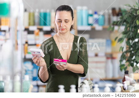 Middle-aged woman customer choosing paracetamol in drugstore Middle-aged woman customer choosing paracetamol in drugstore 142255060
