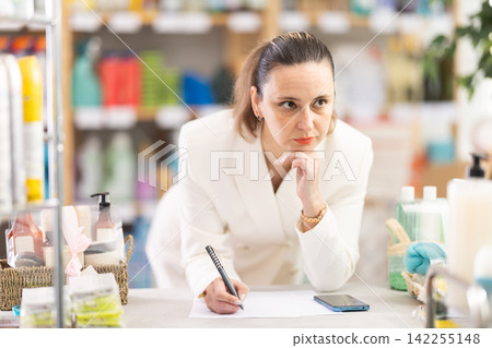 Adult woman conducting inventory with checklist and phone Adult woman conducting inventory with checklist and phone 142255148
