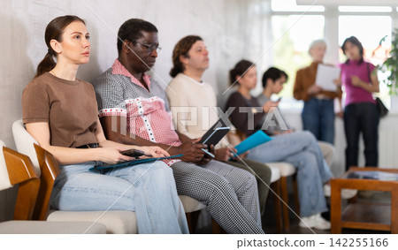 People sitting in line inside a modern office People sitting in line inside a modern office 142255166