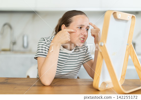 Teenage girl looking in the mirror in the kitchen Teenage girl looking in the mirror in the kitchen 142255172