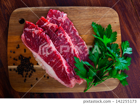 Raw marbled beef steaks with herbs and condiments Raw marbled beef steaks with herbs and condiments 142255173