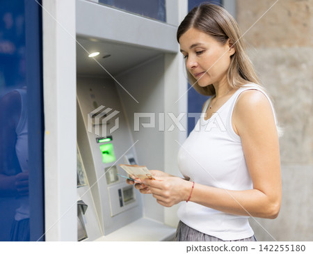 Woman uses outside ATM. Cash withdrawal, user interface Woman uses outside ATM. Cash withdrawal, user interface 142255180
