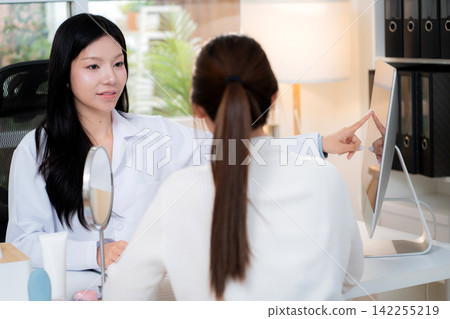 Young asian woman doctor consulting with woman patient in modern aesthetic clinic office pointing. Young asian woman doctor consulting with woman patient in modern aesthetic clinic office pointing. 142255219