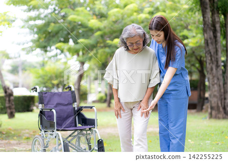 Asian female caregiver helping senior patient walking for physical rehabilitation. Asian female caregiver helping senior patient walking for physical rehabilitation. 142255225