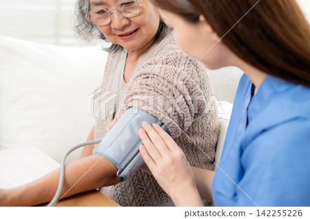 Asian woman nurse measuring blood pressure senior patient. 142255226