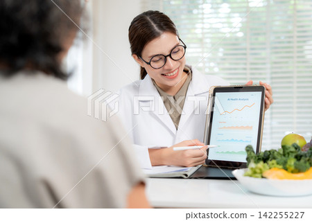 Asian nutritionist showing AI health analysis graph on tablet to senior patient. 142255227