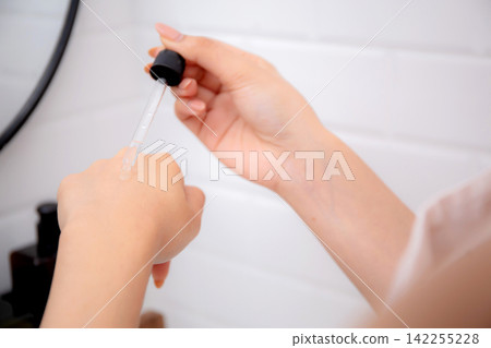 Closeup hands young asian woman applying serum for rejuvenation on hands looking mirror. Closeup hands young asian woman applying serum for rejuvenation on hands looking mirror. 142255228