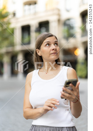 Female pedestrian with phone in summer European capital Female pedestrian with phone in summer European capital 142255243