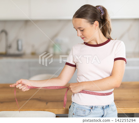 Teenage girl measures her body with centimeter Teenage girl measures her body with centimeter 142255294