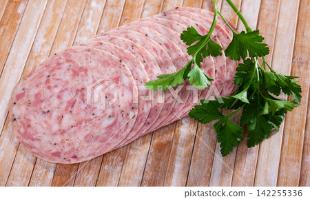 European cuisine raw sausage served with parley on white plate on wooden table European cuisine raw sausage served with parley on white plate on wooden table 142255336