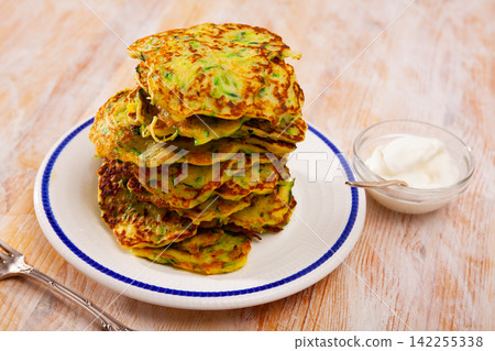 Fritters of courgettes with sour cream Fritters of courgettes with sour cream 142255338