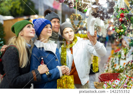 Family choosing Christmas decoration at Christmas market in evening Family choosing Christmas decoration at Christmas market in evening 142255352