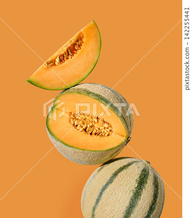 Fresh ripe melon arranged with whole and sliced pieces on a light orange background Fresh ripe melon arranged with whole and sliced pieces on a light orange background 142255441