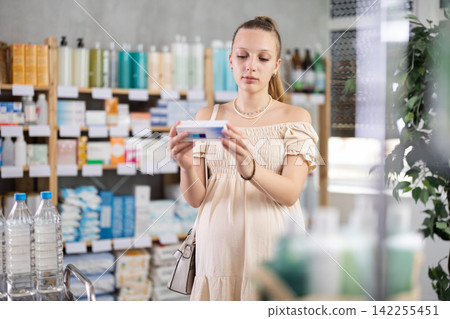 Pregnant woman customer choosing ointment in box in drugstore 142255451