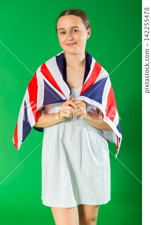 Teenage girl holding UK flag in front of green screen Teenage girl holding UK flag in front of green screen 142255478