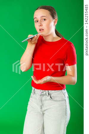 Teenage girl sending audio message in front of green screen 142255485