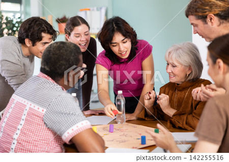 Group of focused people playing board game around a table Group of focused people playing board game around a table 142255516