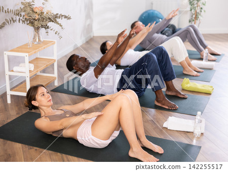 Young woman doing pilates in group in studio Young woman doing pilates in group in studio 142255517