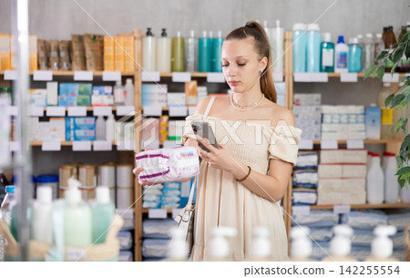 Girl in summer clothes scans code on package of feminine pads to check expiration date Girl in summer clothes scans code on package of feminine pads to check expiration date 142255554