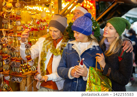 Friendly family chooses Christmas souvenirs and toys Friendly family chooses Christmas souvenirs and toys 142255583