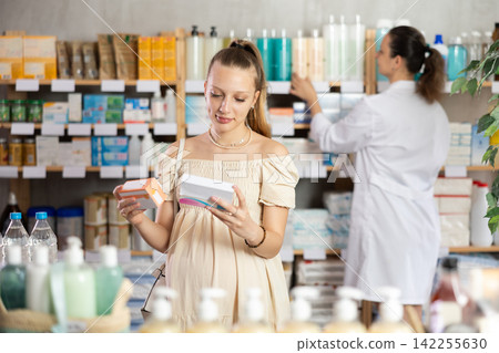 Pregnant girl chooses pills at pharmacy Pregnant girl chooses pills at pharmacy 142255630