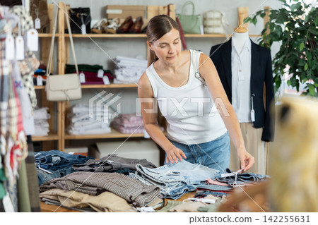 Adult woman choosing jeans in clothing store Adult woman choosing jeans in clothing store 142255631