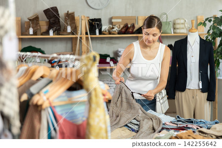 Adult woman choosing pants in clothing store Adult woman choosing pants in clothing store 142255642