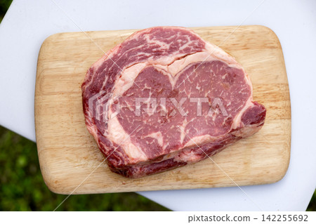 Raw Beef Steak on Wooden Cutting Board Ready for Grilling Outdoors Raw Beef Steak on Wooden Cutting Board Ready for Grilling Outdoors 142255692